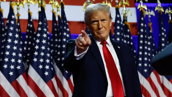 Trump pointing in front of a row of American flags