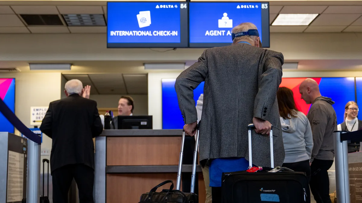 Travelers wait in line at a Delta airlines check-in counter.