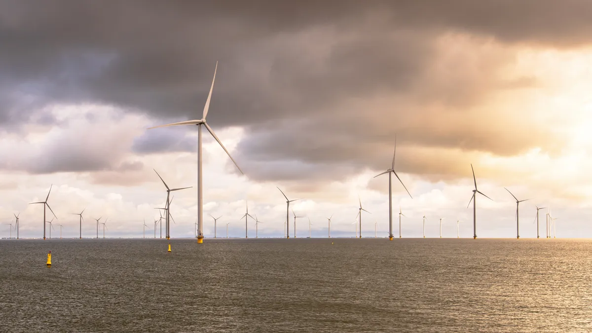 A group of wind turbines in the water of IJsselmeer under a cloudy sky.