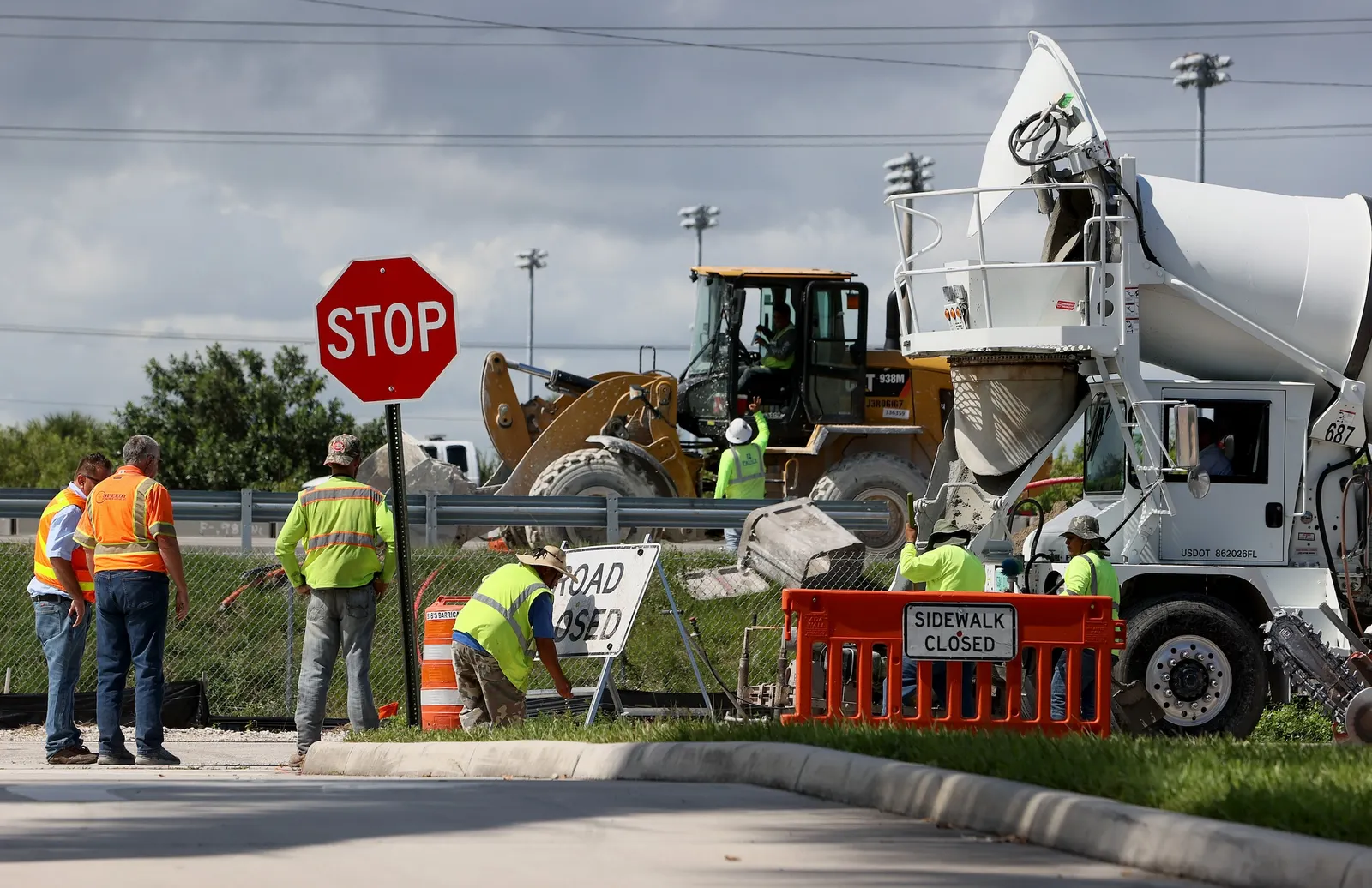 People with heavy machinery wearing safety vests at a road construction site.