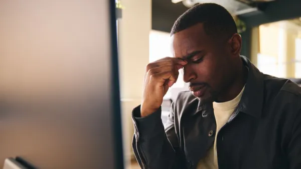 Person with their head down pinching the bridge of their nose in frustration.