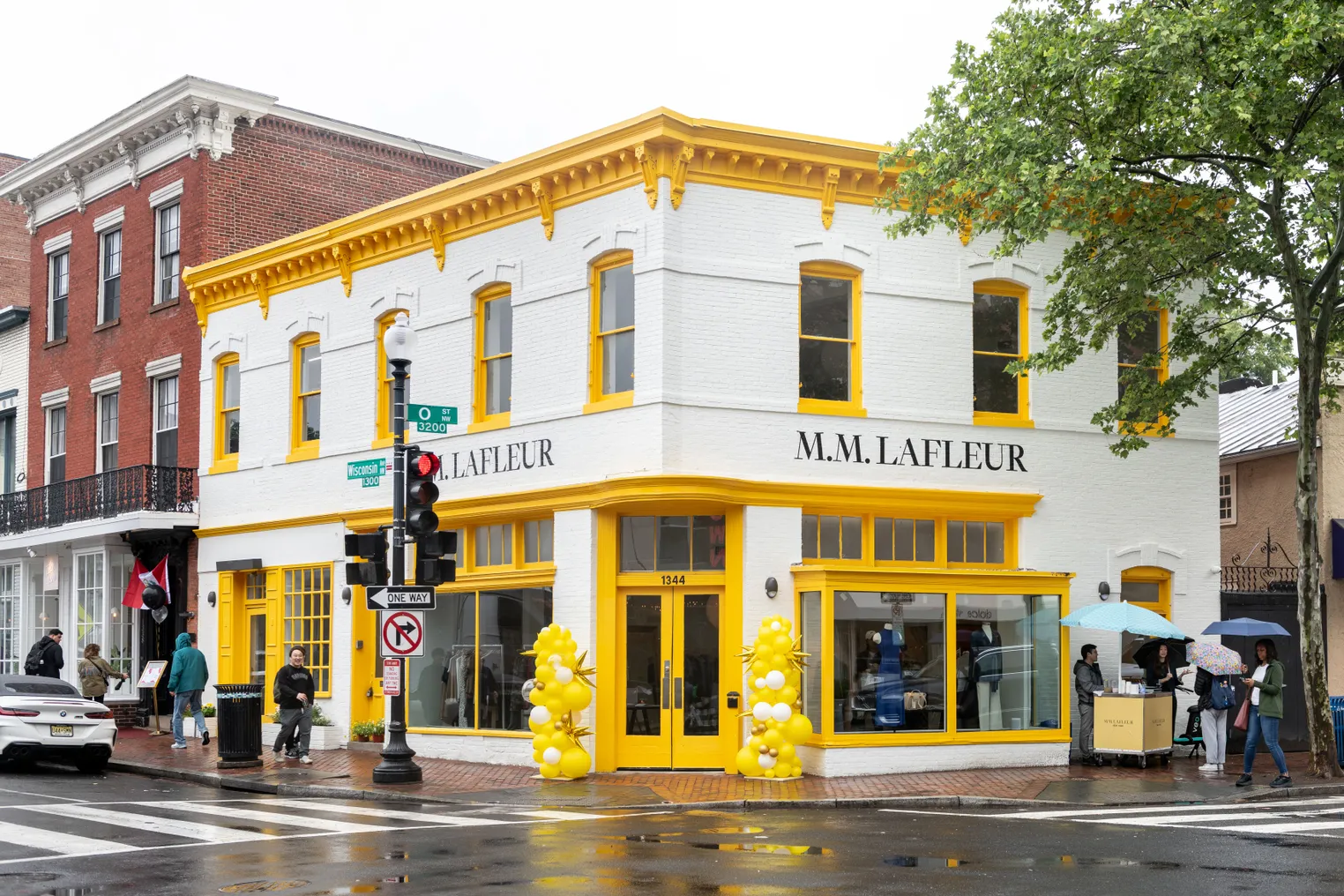 A white store with yellow trim, with the words "M.M. LaFleur" painted in black.