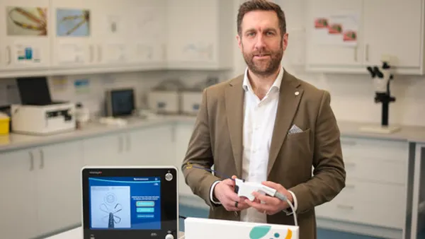 The CEO of Neurent Medical displays the Neuromark device with laboratory equipment in the background.
