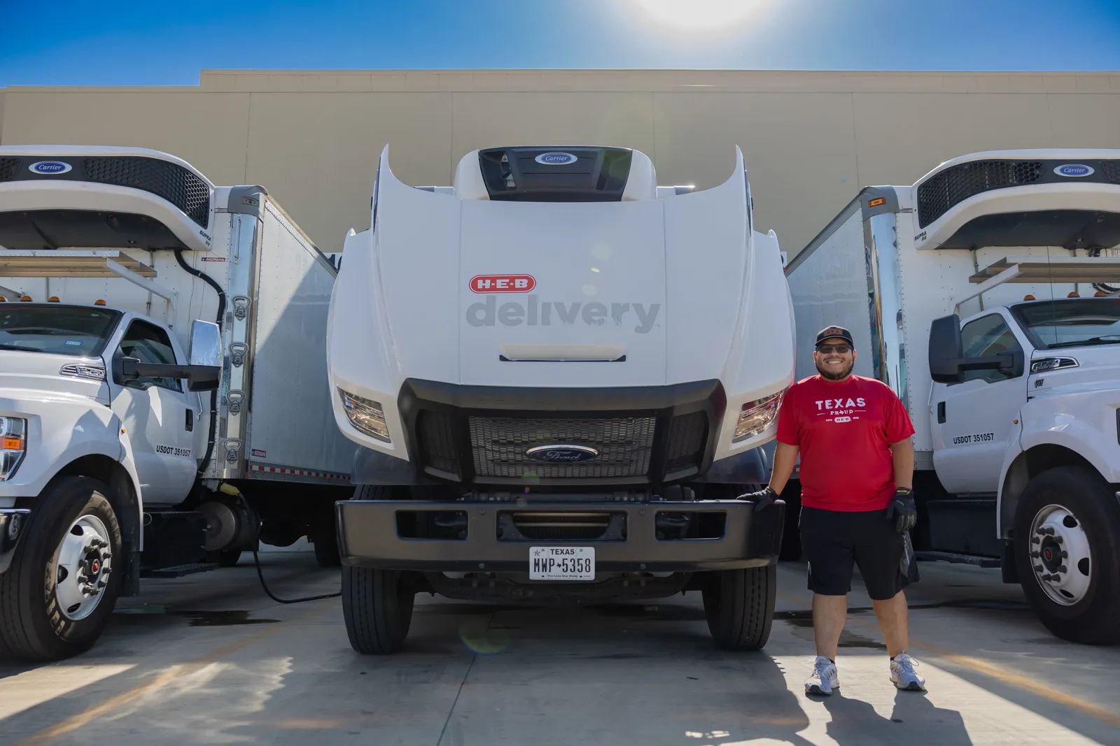 A person in front of a white "H-E-B delivery"-branded vehicle.