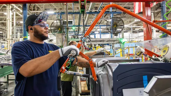 A worker builds an appliance on a factory floor.