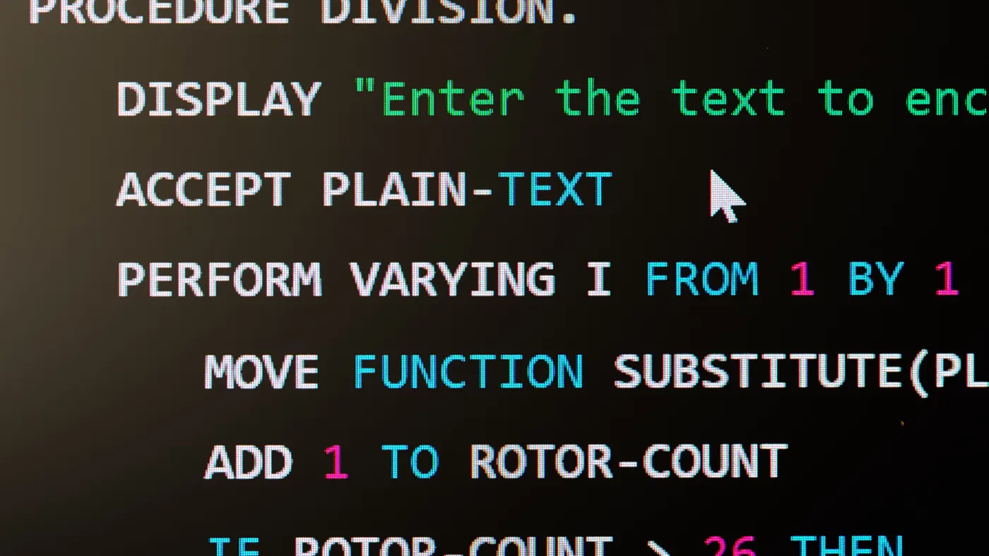 A computer screen displays a snippet of legacy COBOL programming language code.
