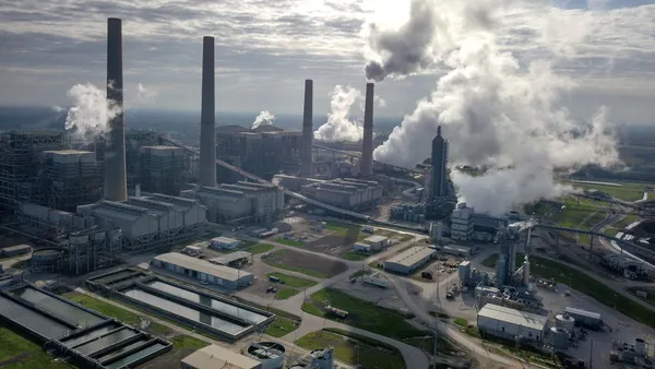 An aerial view of a power plant with steam rising from one of four smokestacks.