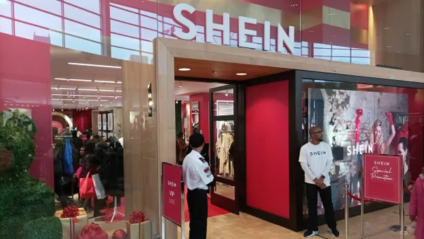 A Shein popup storefront. Two people stand in front of the doors wearing Shein T-shirts.