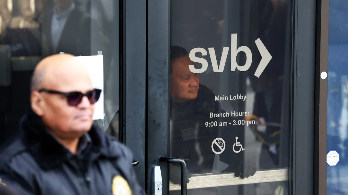 A security guard at Silicon Valley Bank peers through the front door of the bank branch