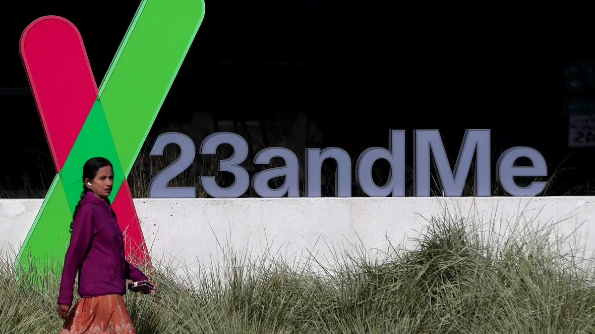 A woman walks past 23andMe's logo in front of its California headquarters.