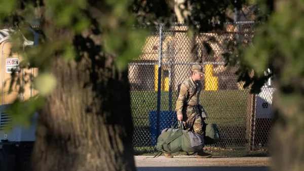 An individual approaches an Army training facility carrying a duffel bag.