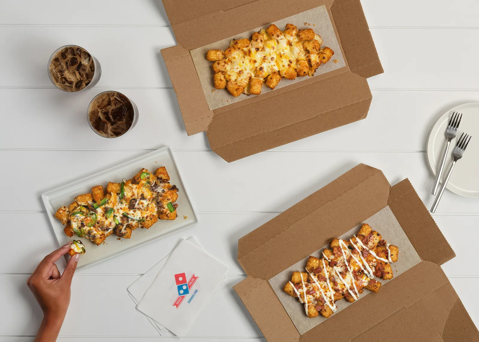 A promotional image showing three boxes of Domino's loaded tots.