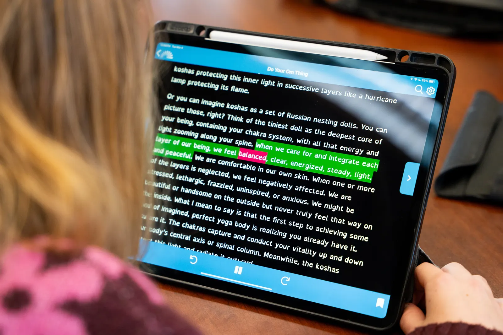 Part of a student's head and hand is seen holding a device with text that is highlighted.