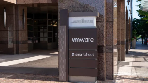 A sign bearing the name of software company VMware and smartsheet is visible on a city street.