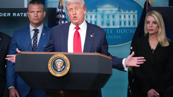 President Donald Trump stands at a podium with Seal of the President of the United States on it, with Pete Hegseth on his right and Pam Boni on his left,