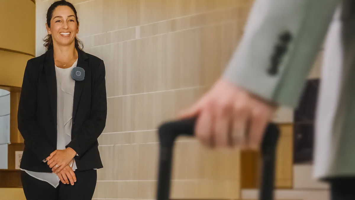 A staffer wears a safety device on the lapel of their blazer.