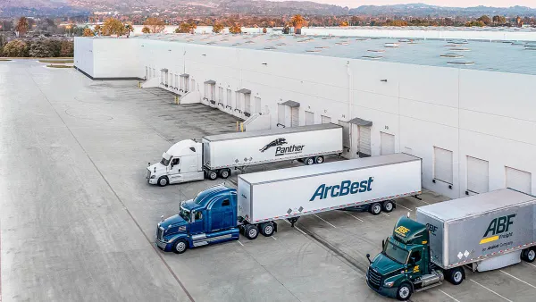A warehouse showing three freight trucks parked and backed up on doors.
