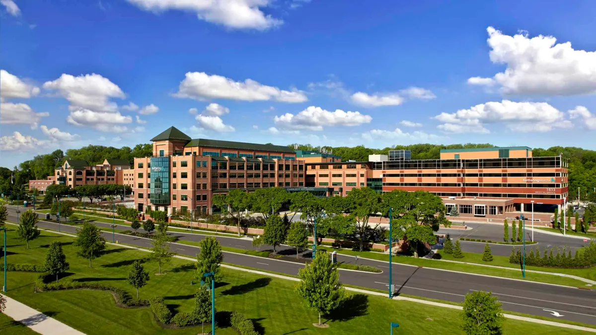 Wide-angle view of Kettering Health Medical Complex on a sunny day, featuring multiple connected buildings surrounded by lawns and trees.
