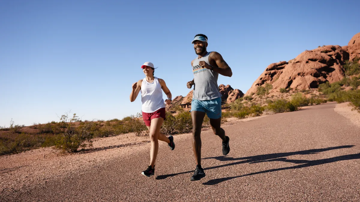 Two people in Brooks Running apparel and shoes run down a road.