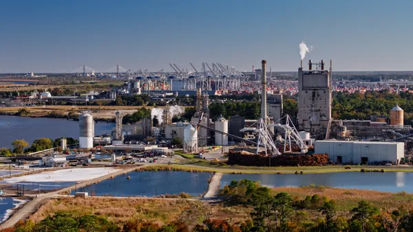 An aerial overview of a paper mill facility near a body of water.