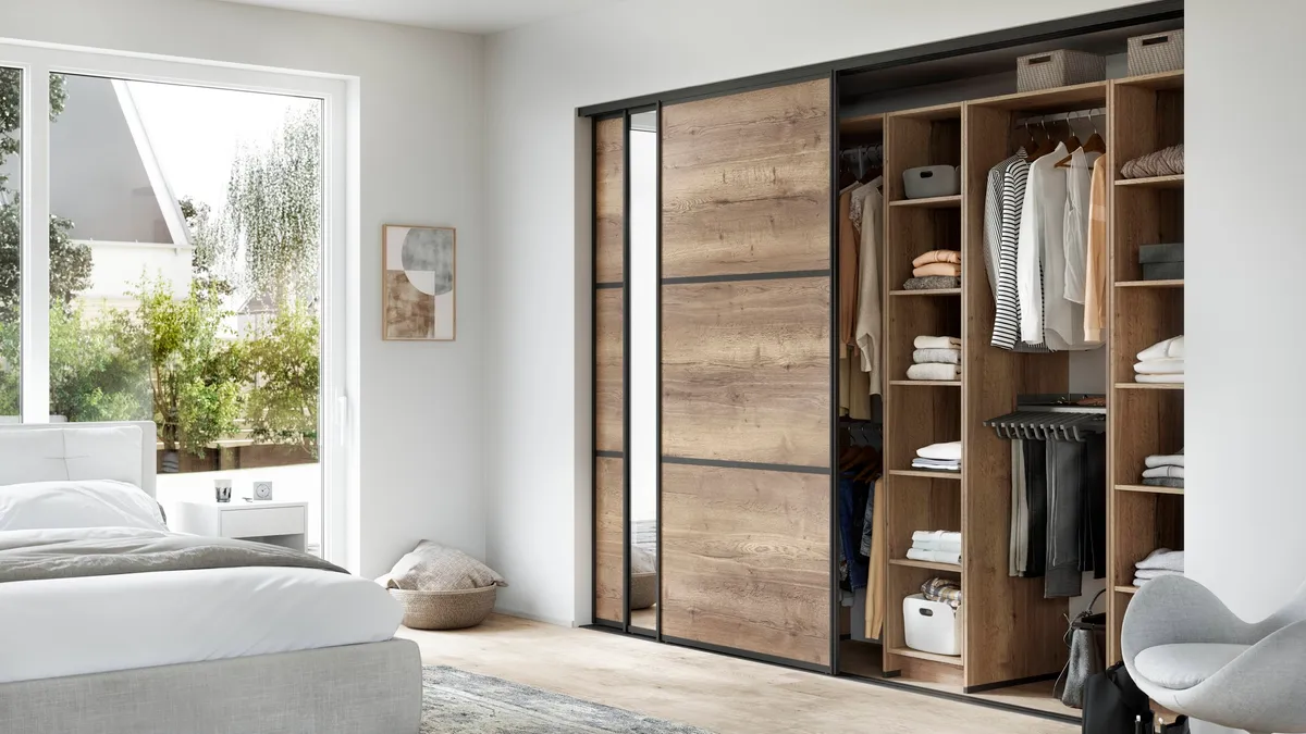 A bedroom with a closet with sliding doors.