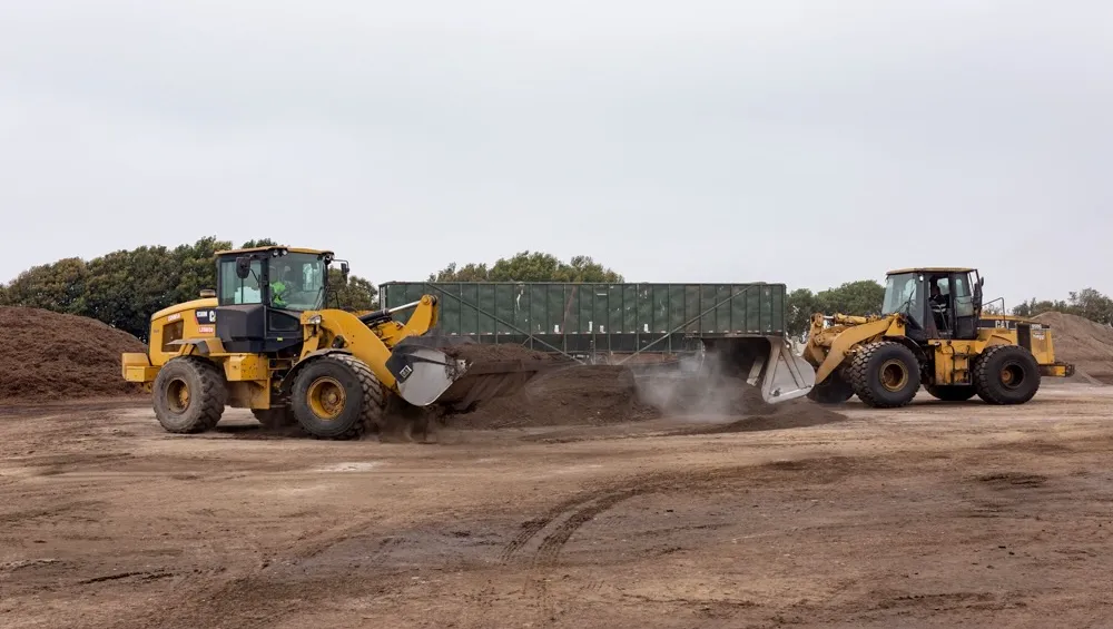 Two tractors scooping compost