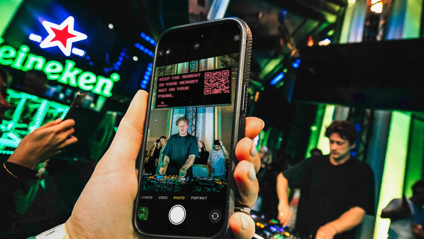A smartphone shows a secret message from Heineken during a DJ performance at ADE