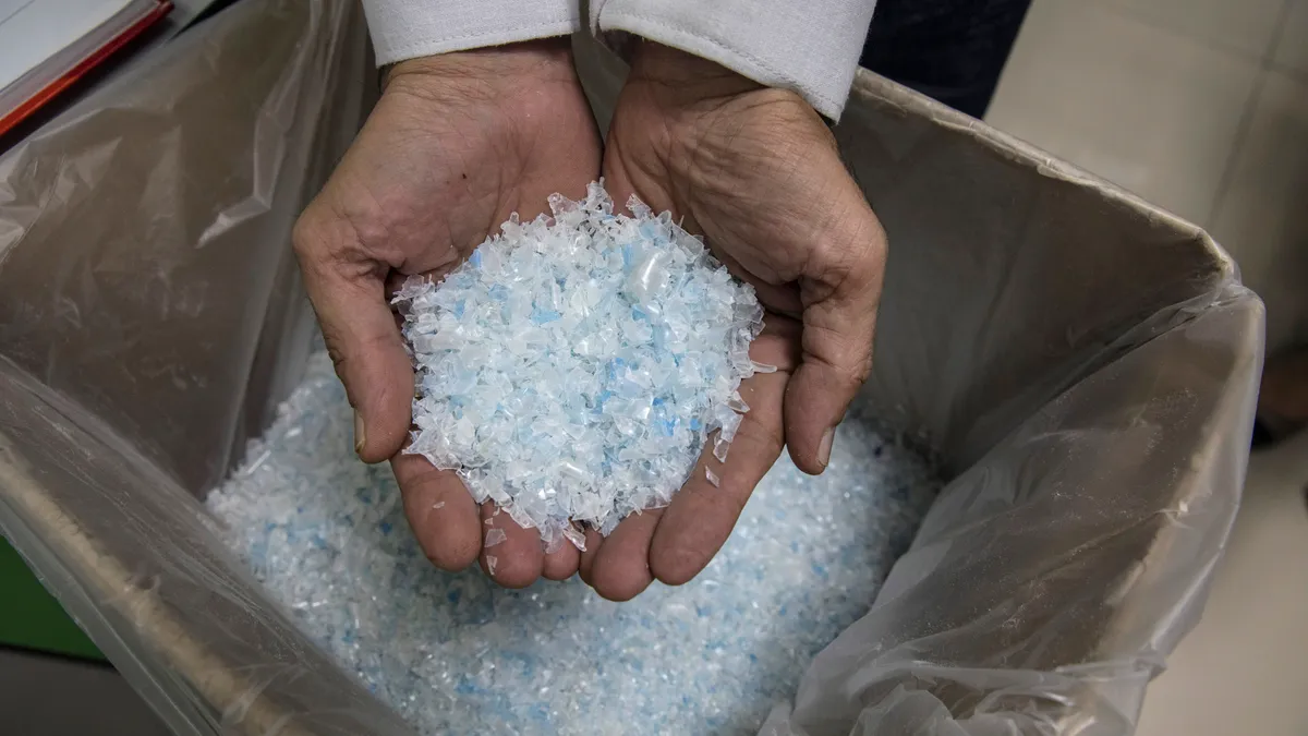 hands scoop up a handful of recycled plastic flake