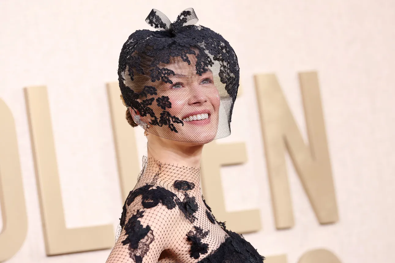 Rosamund Pike wears a veiled headpiece and netted vintage Dior dress.