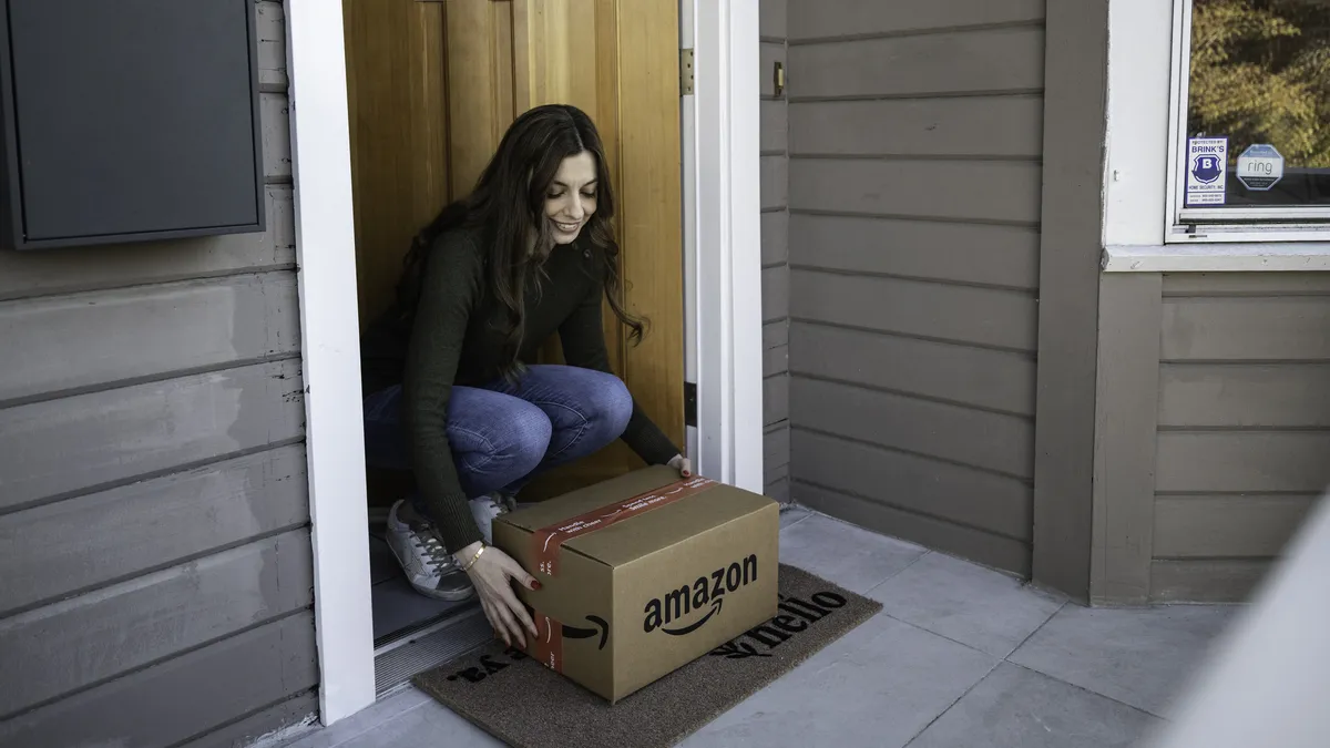 A person taking in a package from their front doorstep.