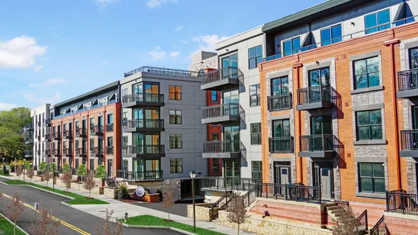 Four-story multi-colored apartment building with balconies.