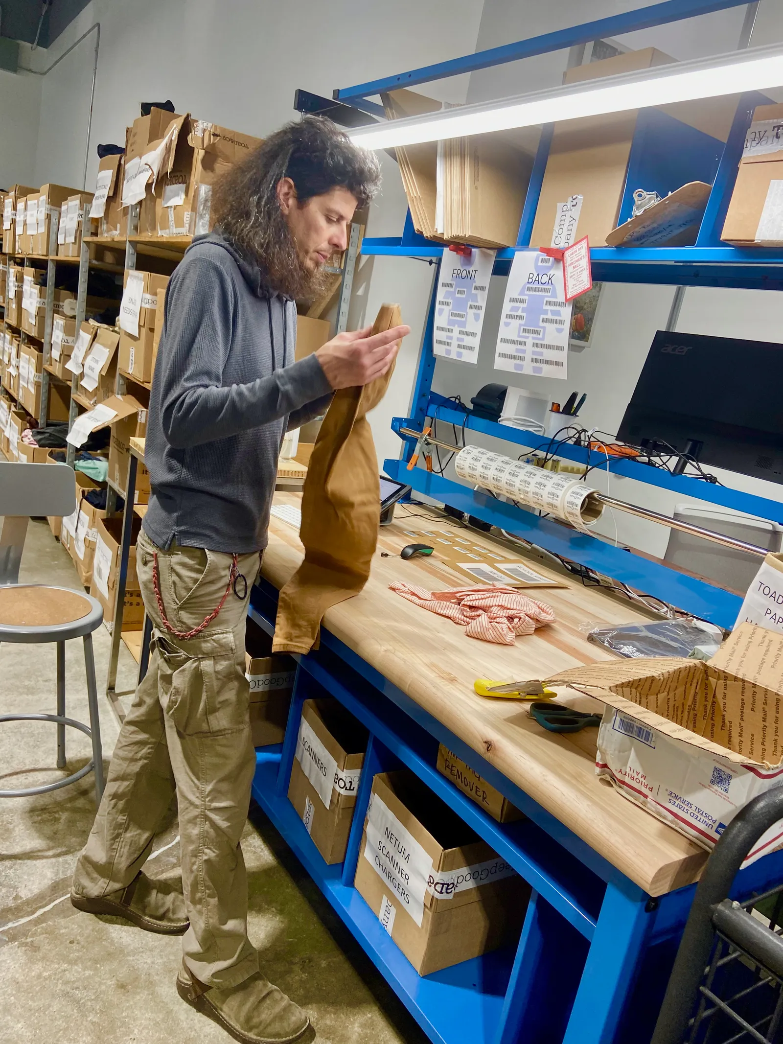 A person at a workbench, surrounding by boxes.