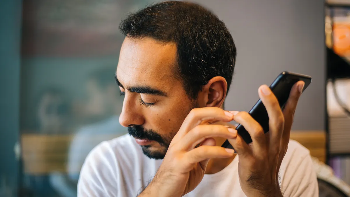 A man holds up a phone to his ear.