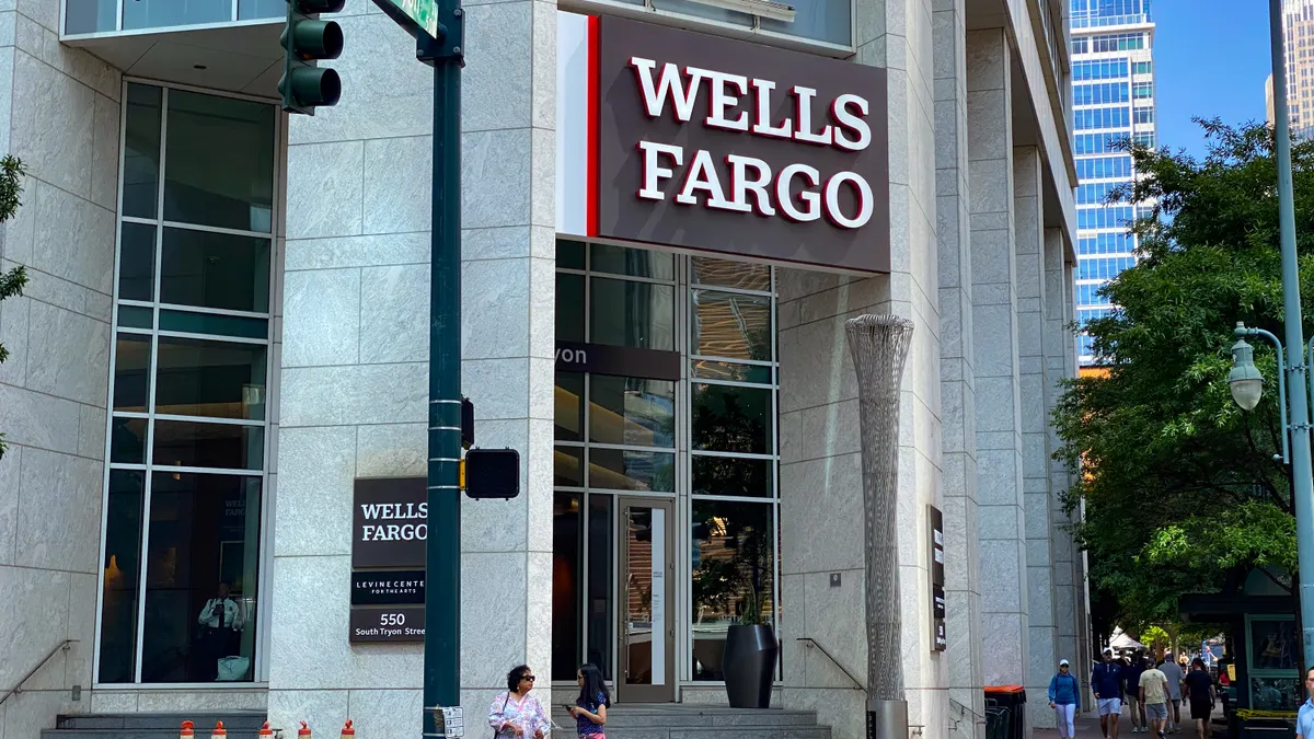 A modern building facade with "Wells Fargo" signage above the entrance is shown, as people pass by on the street.