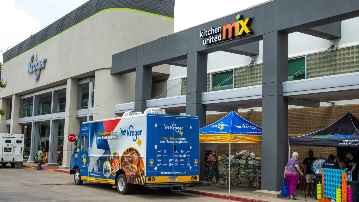 Exterior of a Kroger store with a "Kitchen United Mix" sign on the building and delivery van.