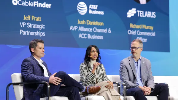 Three people sit on a stage