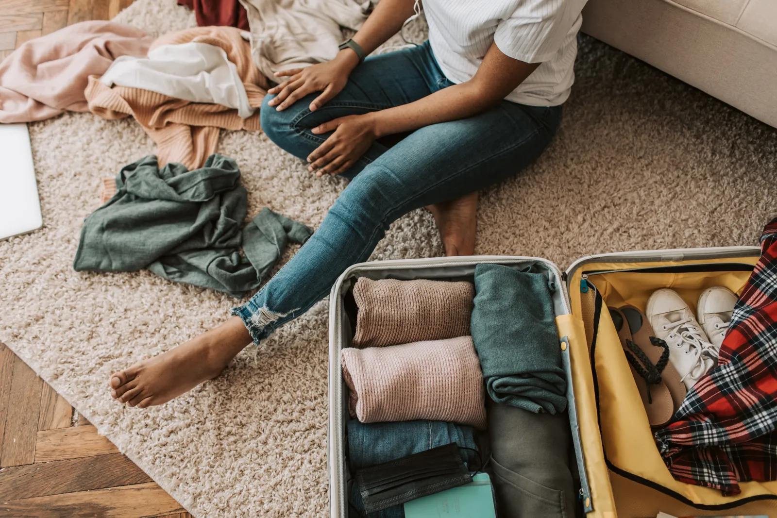 Medium shot of a Black woman packing a suitcase with clothes