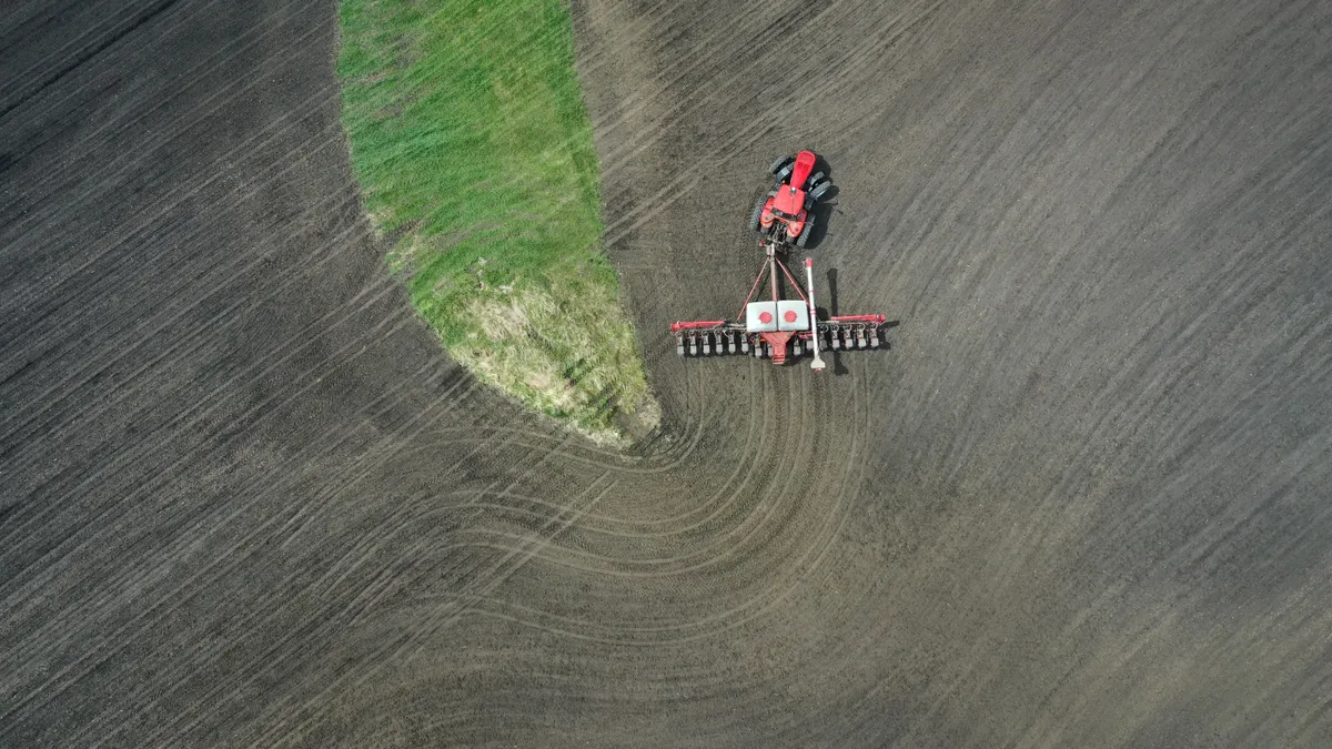 An aerial view shows a tractor on a farm planting