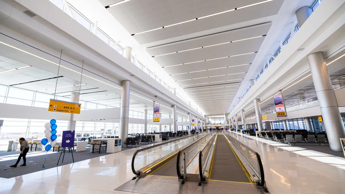 An airy white concourse space with moving sidewalks and seating.