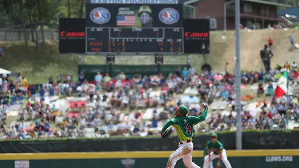 A little league baseball player throws a pitch.