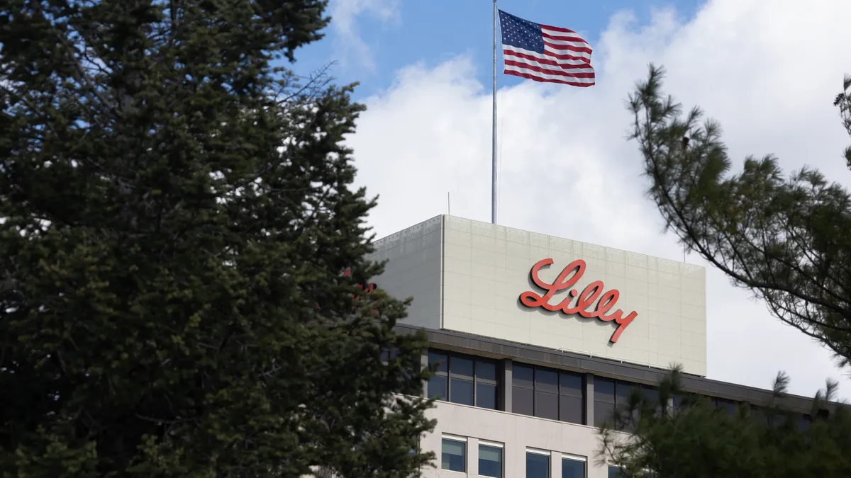 A U.S. flag flying above a building showing a sign with the word Lilly written in red.