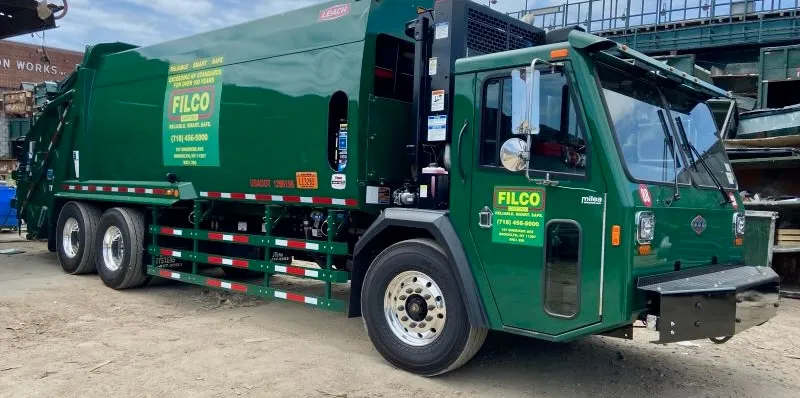 Green waste collection truck sitting in parking lot