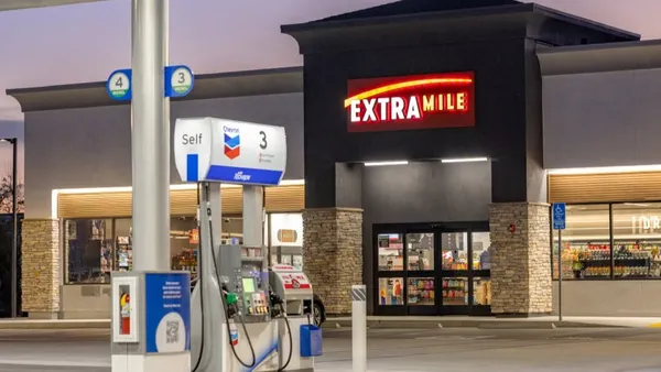 A photo of the exterior of a convenience store and gas station. A sign over the store door says ExtraMile.