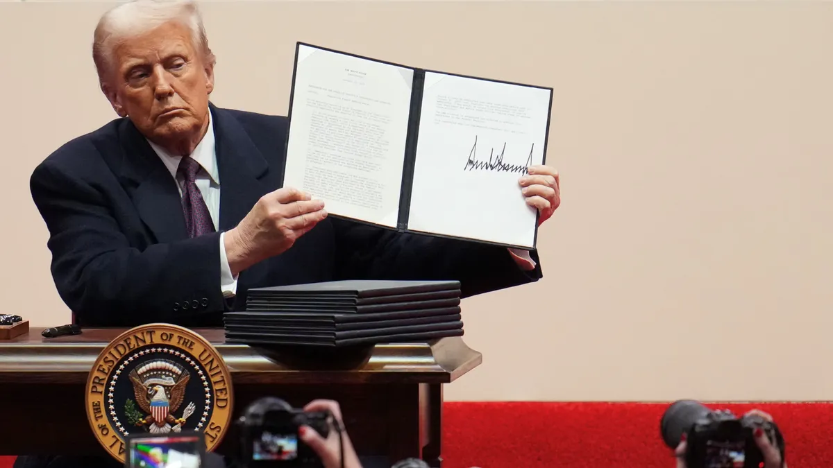 President Donald Trump holds up a signed executive order