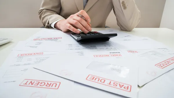 Close-up Of Businessman Calculating With Calculator Unpaid Bills