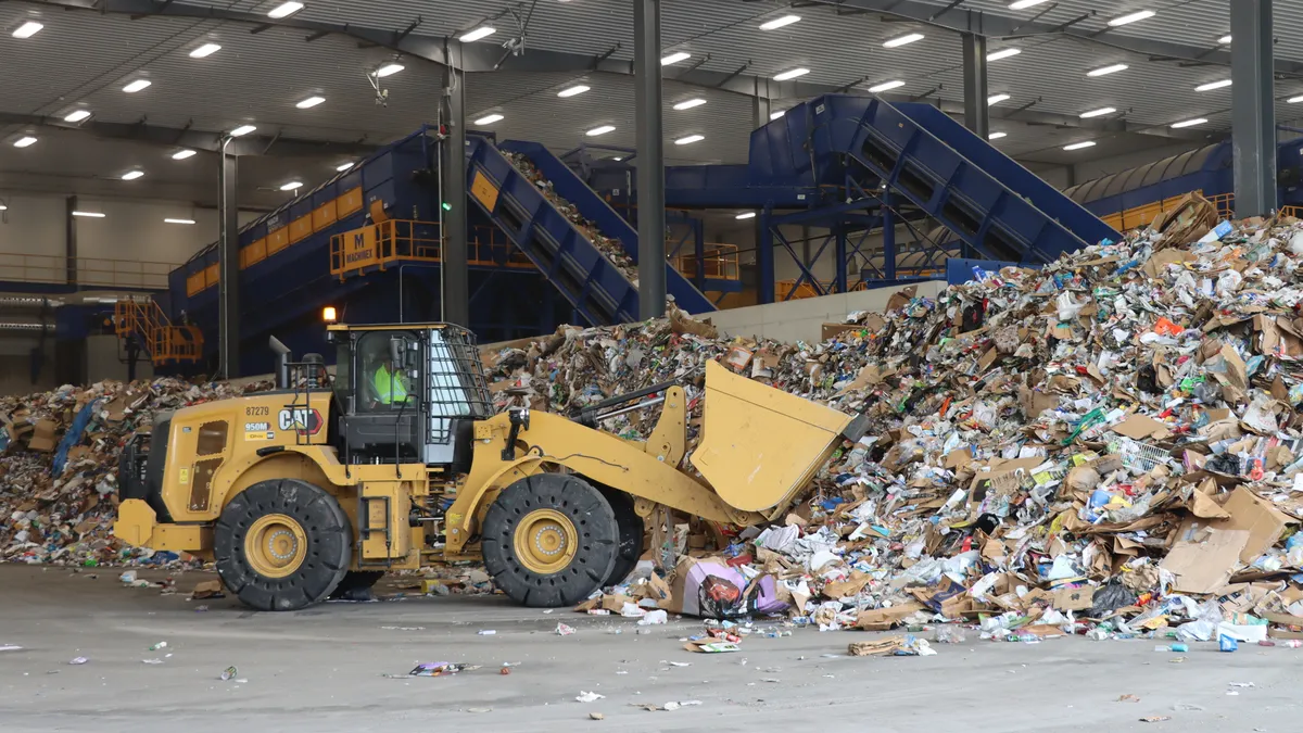 A front loader collects recycled materials in a recycling facility.