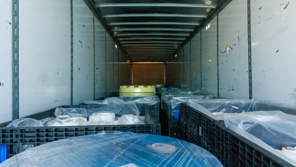 Several plastic wrapped barrels sit in crates in the back of a trailer truck.