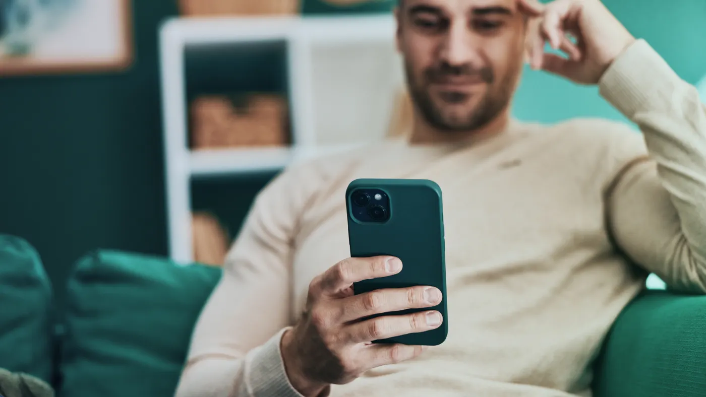Person sitting on couch using smartphone