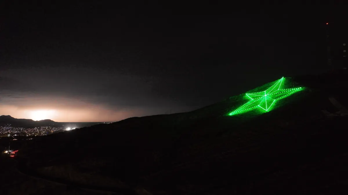 A green star light fixture shinning on a hill at night