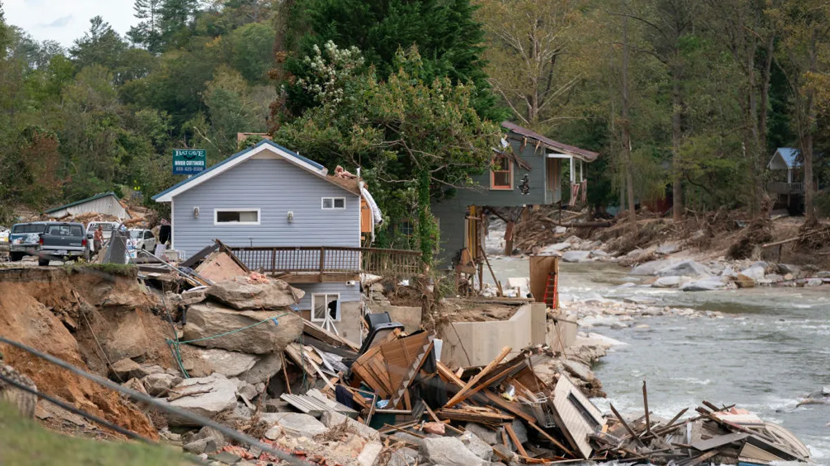 Building debris falling into a river. Other houses still stand by the river.